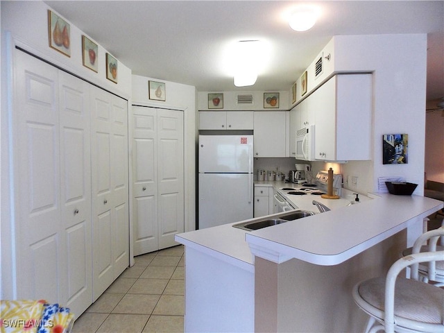 kitchen featuring white appliances, light tile patterned floors, a peninsula, light countertops, and white cabinetry