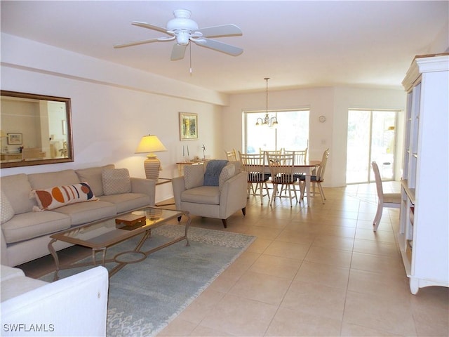 living area with light tile patterned flooring and ceiling fan with notable chandelier