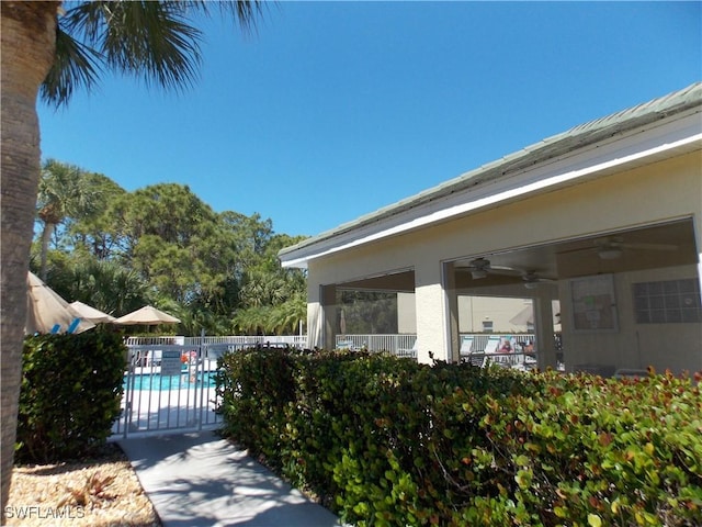 pool featuring a ceiling fan and fence