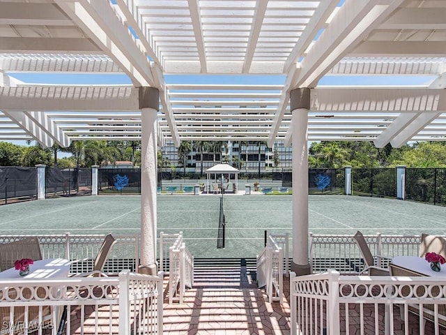 view of property's community featuring a tennis court, a pergola, and fence