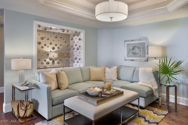 living room with baseboards, a raised ceiling, wood finished floors, and crown molding