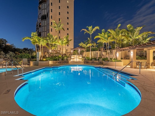 pool at twilight featuring a patio and a community pool