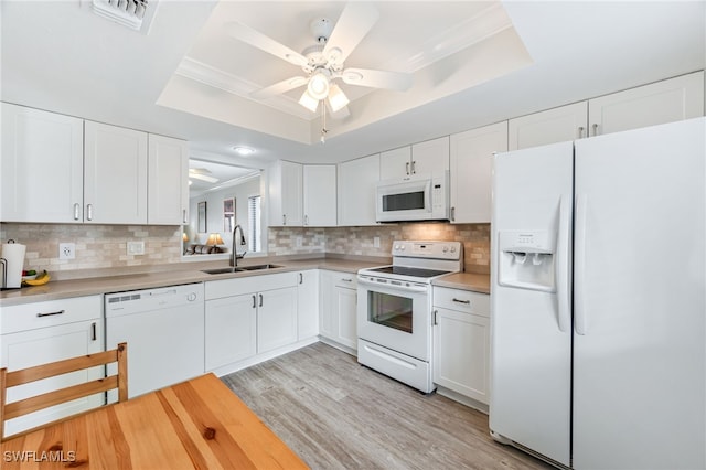 kitchen featuring a sink, visible vents, white appliances, and a raised ceiling