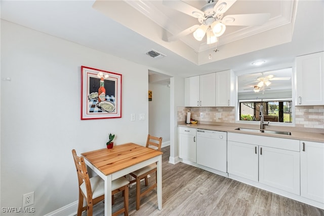 kitchen with tasteful backsplash, visible vents, a tray ceiling, white dishwasher, and a sink