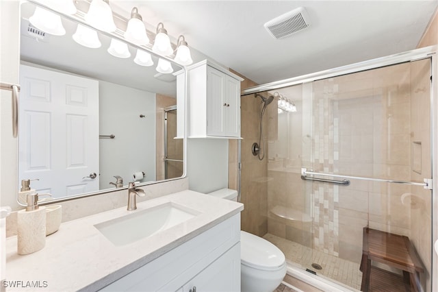 bathroom with vanity, a shower stall, toilet, and visible vents