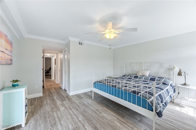 bedroom with visible vents, baseboards, ornamental molding, light wood-style floors, and a ceiling fan