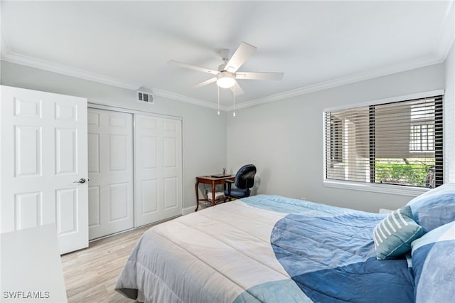 bedroom with crown molding, a closet, visible vents, and light wood finished floors