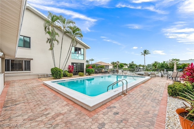 pool with a patio area and fence