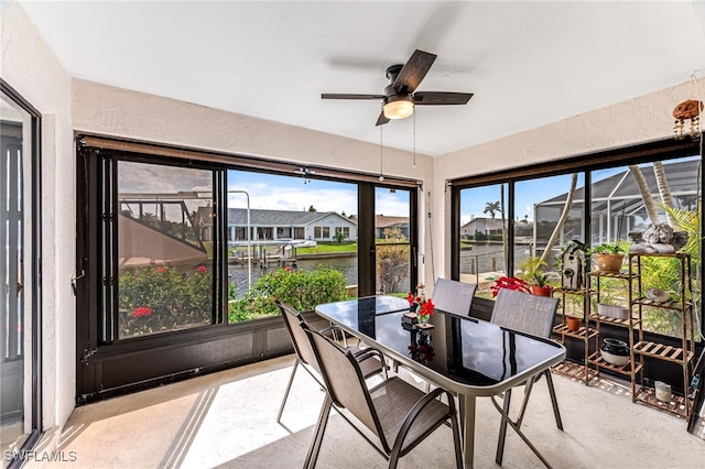 sunroom / solarium featuring a ceiling fan and a water view