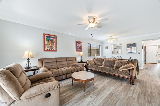 living room with baseboards, light wood-type flooring, crown molding, and a ceiling fan