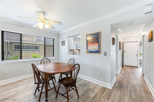 dining space featuring baseboards, crown molding, light wood-style floors, and a ceiling fan