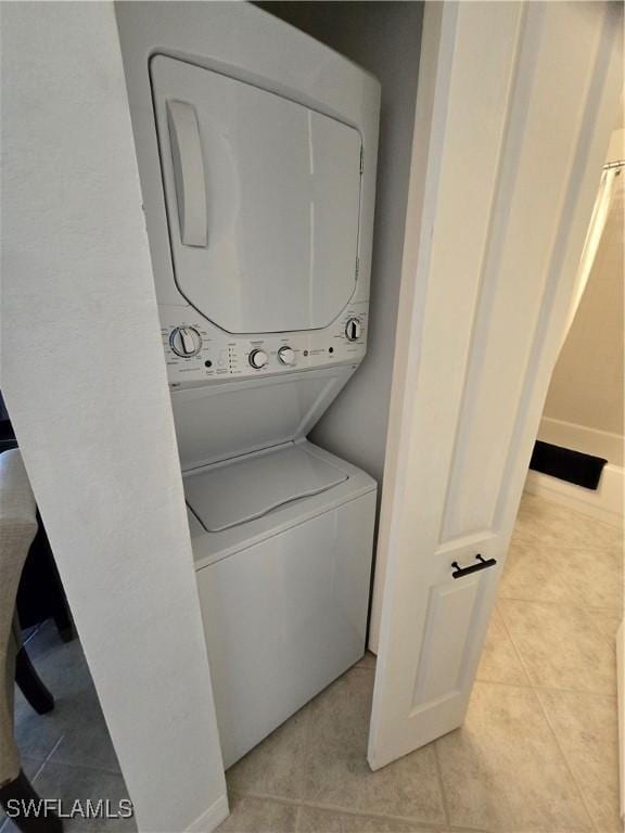 laundry area featuring laundry area, light tile patterned flooring, and stacked washing maching and dryer