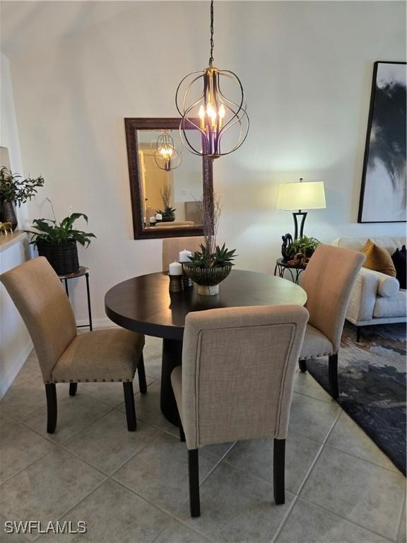 dining room with lofted ceiling, a notable chandelier, and light tile patterned flooring