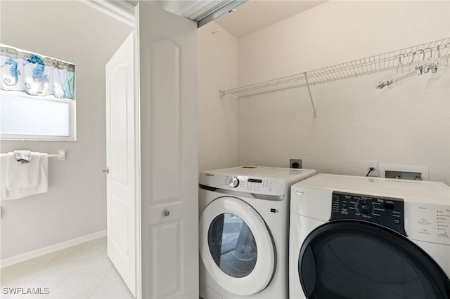 washroom featuring light tile patterned floors, laundry area, baseboards, and separate washer and dryer