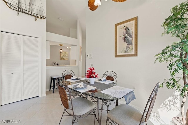 dining space featuring a high ceiling, light tile patterned floors, and a ceiling fan