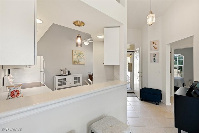 kitchen featuring pendant lighting, light countertops, light tile patterned floors, white cabinets, and range