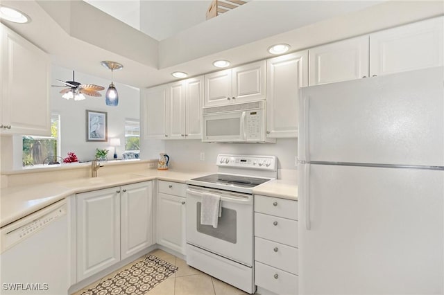 kitchen with a sink, white appliances, white cabinets, light countertops, and light tile patterned floors