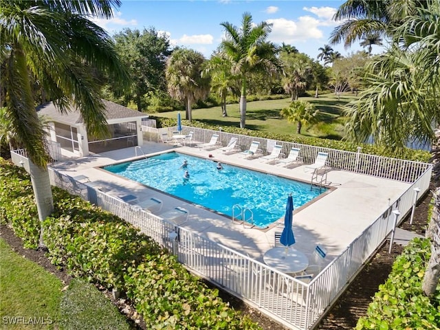 pool featuring a patio, fence, a lawn, and a sunroom