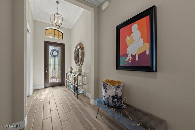 entrance foyer with wood finish floors, baseboards, an inviting chandelier, and crown molding