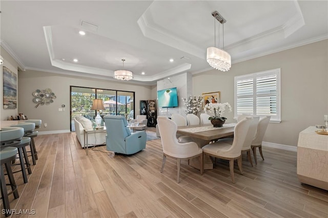 dining space featuring visible vents, light wood-style flooring, crown molding, and a tray ceiling