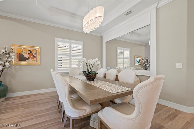 dining area with light wood-type flooring, visible vents, ornamental molding, an inviting chandelier, and baseboards