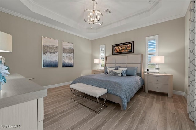 bedroom with a tray ceiling, light wood-style floors, and visible vents