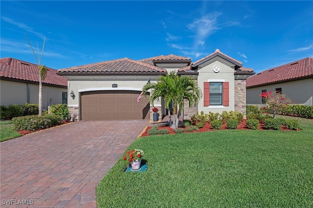 mediterranean / spanish-style home with a front yard, stucco siding, a garage, stone siding, and decorative driveway