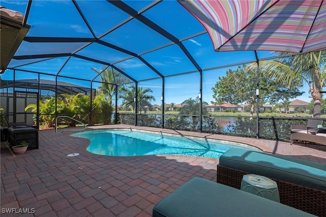 outdoor pool with glass enclosure, a water view, and a patio area