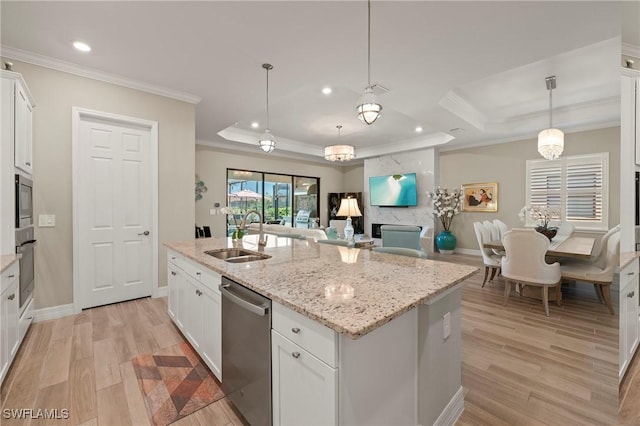 kitchen featuring a tray ceiling, light wood-style flooring, a sink, ornamental molding, and stainless steel appliances