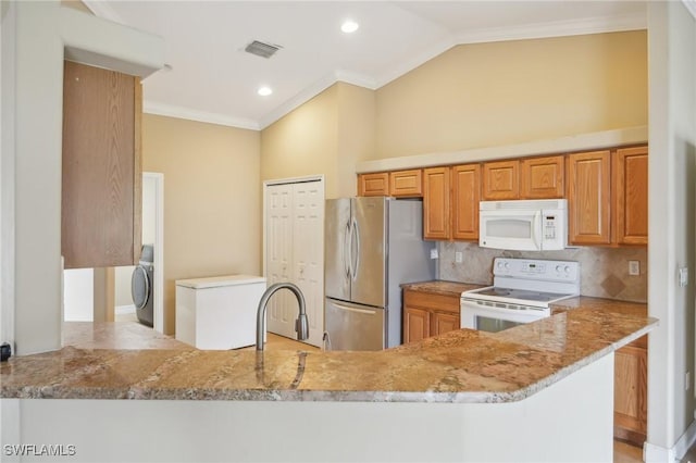 kitchen with backsplash, crown molding, light stone counters, washer / dryer, and white appliances