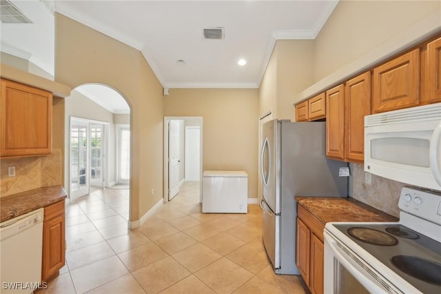 kitchen featuring visible vents, white appliances, arched walkways, light tile patterned flooring, and crown molding