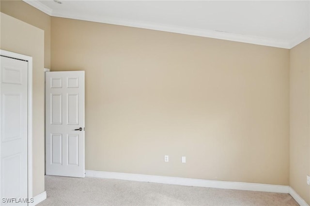 empty room featuring ornamental molding, baseboards, and light carpet