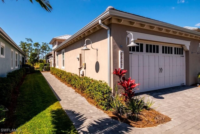 view of property exterior with an attached garage, a lawn, and stucco siding