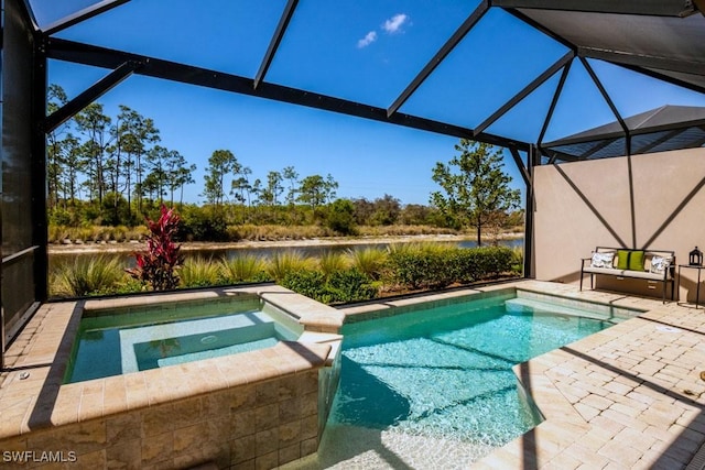 view of pool featuring glass enclosure, a patio area, a water view, and a pool with connected hot tub