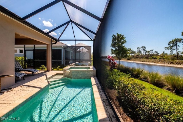 view of pool featuring glass enclosure, a pool with connected hot tub, a patio, and a water view