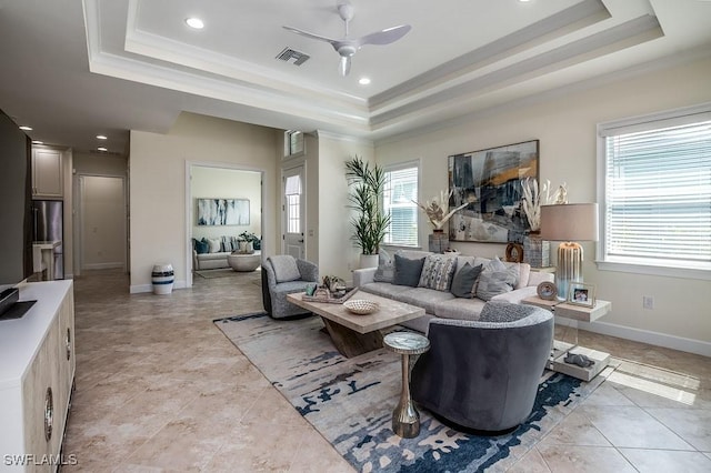 living room with light tile patterned floors, a ceiling fan, visible vents, baseboards, and a raised ceiling