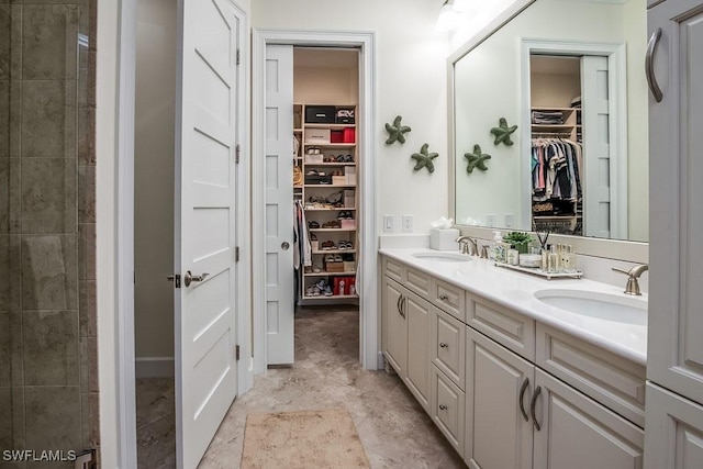 bathroom featuring double vanity, a spacious closet, and a sink