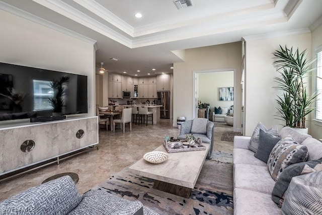 living room featuring visible vents, recessed lighting, a tray ceiling, and ornamental molding