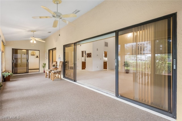 unfurnished sunroom with vaulted ceiling, a ceiling fan, and visible vents