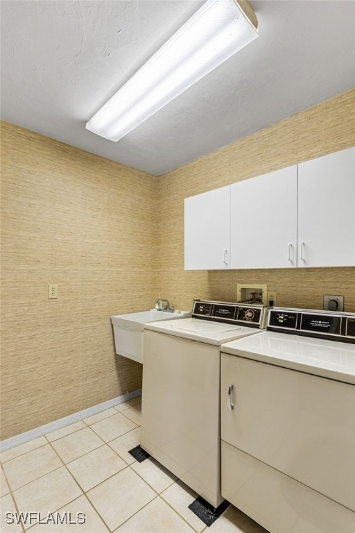 laundry area featuring washer and clothes dryer, light tile patterned flooring, cabinet space, and a sink