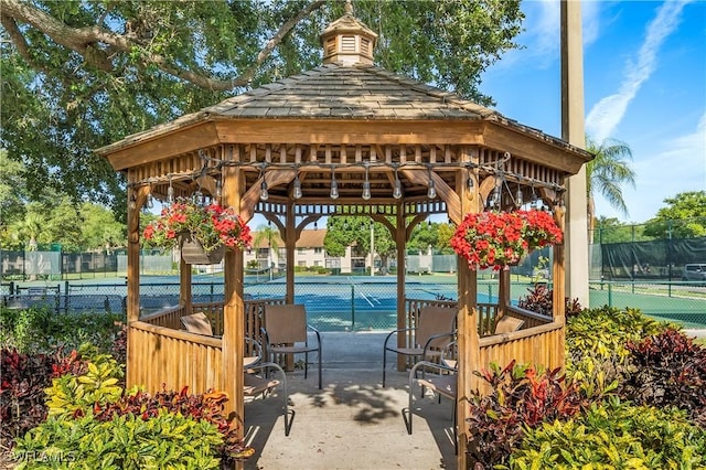 view of property's community featuring a gazebo, a tennis court, and fence