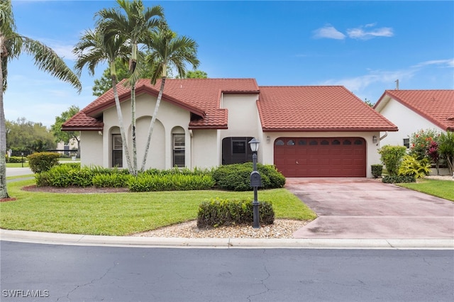 mediterranean / spanish-style home with a tile roof, concrete driveway, a front yard, stucco siding, and a garage