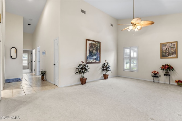 interior space featuring a high ceiling, visible vents, carpet, and a healthy amount of sunlight