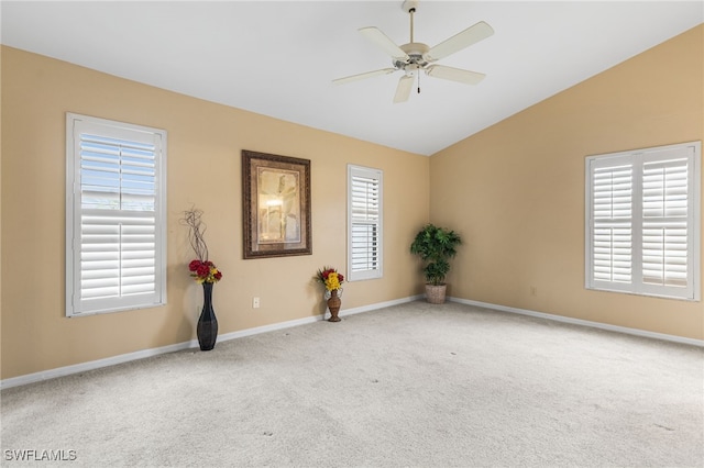 empty room with a healthy amount of sunlight, ceiling fan, carpet flooring, and vaulted ceiling