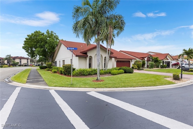 mediterranean / spanish home featuring a front yard, stucco siding, a garage, a tile roof, and a residential view