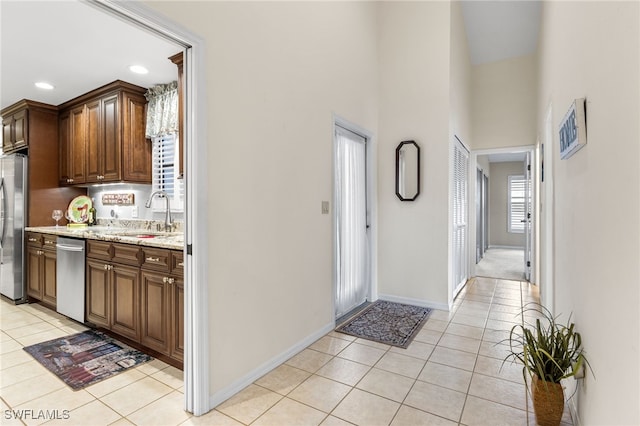 hallway with a sink, recessed lighting, a high ceiling, light tile patterned floors, and baseboards