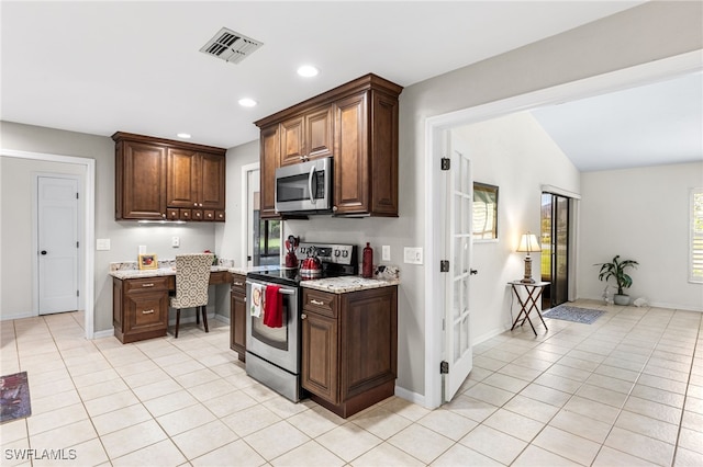 kitchen featuring light tile patterned floors, stainless steel appliances, visible vents, and built in desk