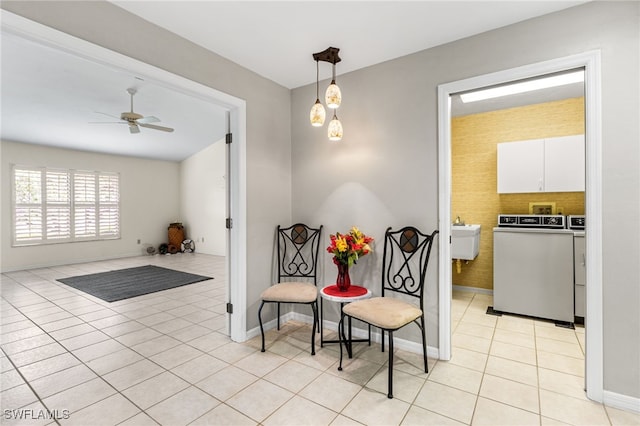 living area featuring light tile patterned floors, washing machine and dryer, baseboards, and ceiling fan