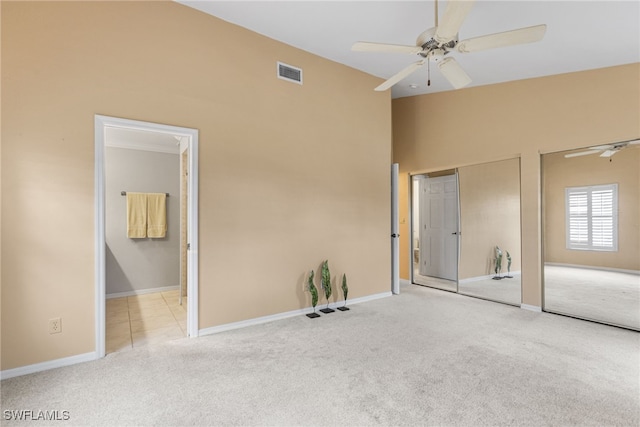 unfurnished bedroom featuring visible vents, multiple closets, baseboards, carpet flooring, and lofted ceiling