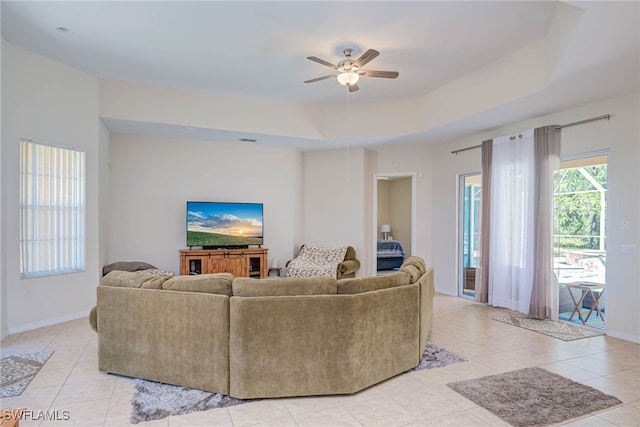 living room featuring light tile patterned floors, a tray ceiling, baseboards, and visible vents